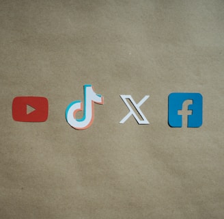 Four social media platform logos are arranged on a brown background. From left to right, the logos are for YouTube in red, TikTok in a combination of red, blue, and white, X in white, and Facebook in blue.